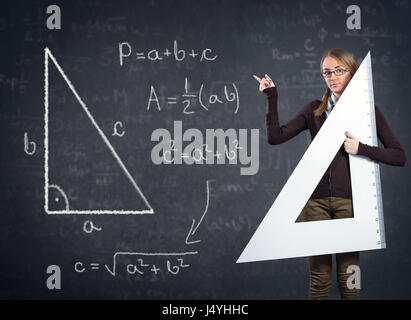 Studentin mit einem großen Lineal zeigt auf Pythagoras auf Tafel Stockfoto