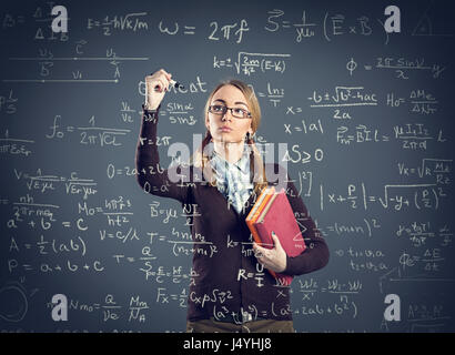 Schüler Mädchen schreiben Formeln auf transparente Wand vorne Ihr Stockfoto