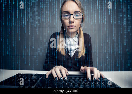 Nerd-Mädchen mit einem Computer mit Binär-Code auf dem Bildschirm Stockfoto