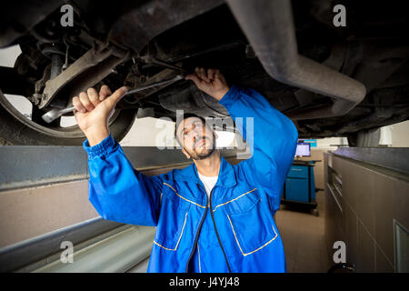 Ein Mechaniker ist den technischen Zustand unter einem Auto Check Stockfoto