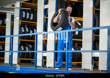 Kfz-Mechaniker tragen Reifen im Reifen Shop Stockfoto