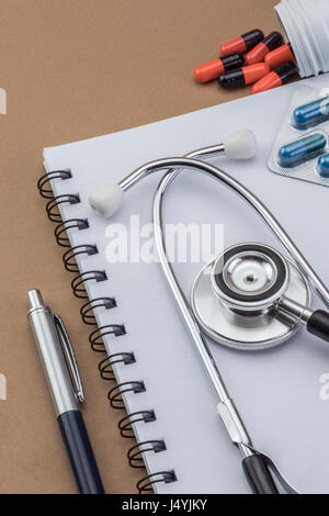 Stethoskop, Tabletten, Ampullen im Arztzimmer auf braunem Hintergrund Draufsicht mockup Stockfoto