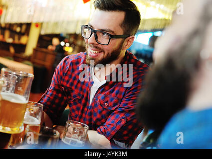 Junge Menschen trinken Bier und reden in einem Café oder einer Kneipe Stockfoto