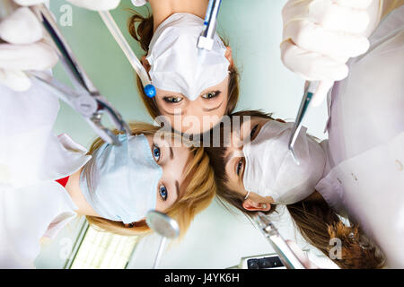 Ansicht der Ärzte, Zahnärzte, die mit chirurgischen Instrumenten, von Patienten nach Operation am Hintergrund Lampe, Decke. Patient Krankenhaus, intensive Pflege un Stockfoto