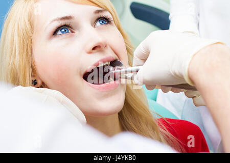 Closeup junge Frau am Zahnarztpraxis Klinik. Männlichen Arzt und Assistentin Extraktionsverfahren mit Pinzette entfernen Patienten Zahn durchführen. Healthcar Stockfoto