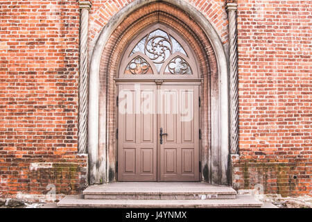 Alten grunge Red brick wall mit großen hölzernen Tür. Stockfoto