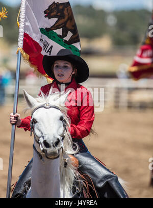 Drill Team Cowgirl reitet in die Arena an der Cottonwood-Rodeo in Kalifornien Stockfoto