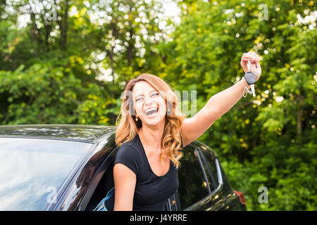 Junge Frau bekommen ihre Schlüssel im Auto. Konzept der Mietwagen oder Kauf Auto. Stockfoto