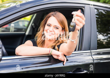 Junge Frau bekommen ihre Schlüssel im Auto. Konzept der Mietwagen oder Kauf Auto. Stockfoto