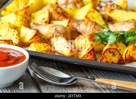 Gebackene Kartoffeln mit Huhn auf ein Backblech legen. Stockfoto