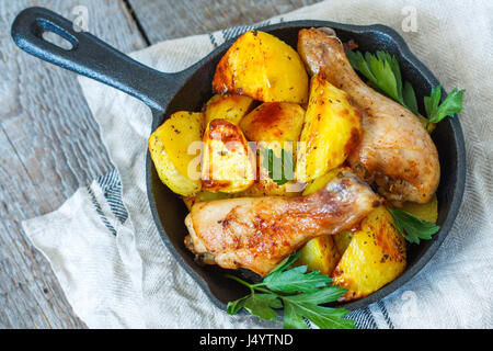 Gebackene Kartoffeln mit Hühnchen in einer gusseisernen Pfanne. Stockfoto