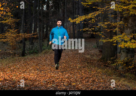 Ein erwachsener Mann läuft in einem Waldweg in Jelenia Gora, Polen. Stockfoto