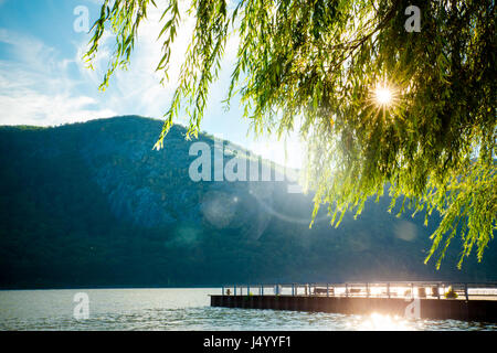 Fluss, Berge und Dock mit Sonne durch die Bäume von Cold Spring NY Stockfoto