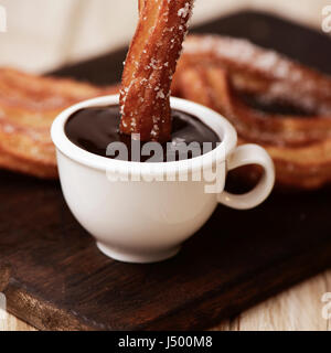 Churros con Chocolate, eine typisch spanische süßen Snack auf einem rustikalen Holztisch Stockfoto