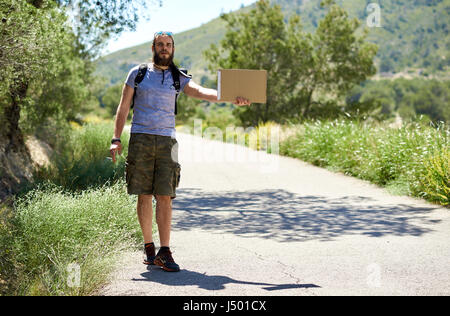 Trampen Reisenden mit einem leeren Pappschild auf einer Bergstraße. Billig reisen. Auto-Stopp Stockfoto