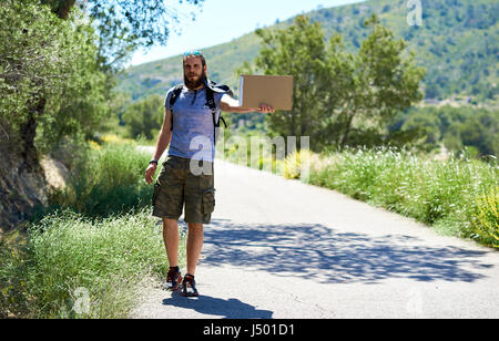 Trampen Reisenden mit einem leeren Pappschild auf einer Bergstraße. Billig reisen. Auto-Stopp Stockfoto