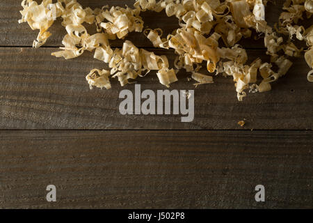 Leichte braune Holzspäne aus des Tischlers Hand Hobel oder Meißel arbeiten auf Holzbrettern Hintergrund mit Textfreiraum Stockfoto