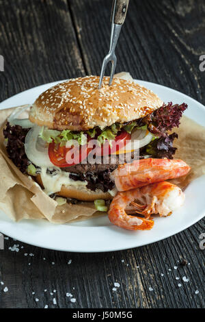 Köstliche frische hausgemachte Surf-And-Turf-Burger auf Holztisch Stockfoto