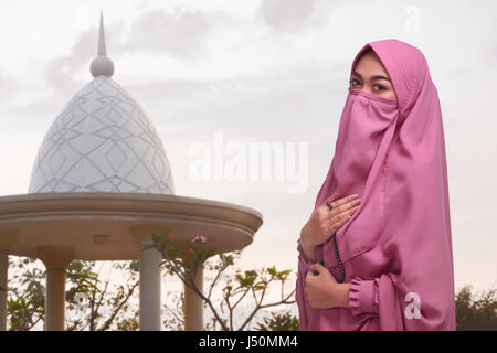 Religiöse muslimische Asiatin mit traditioneller Kleidung hält Gebetskette in der Moschee Stockfoto