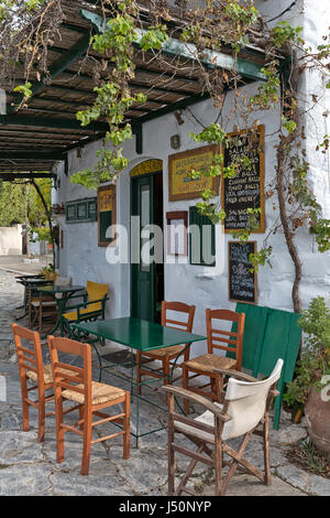 Insel Amorgos, Griechenland - Oktober 2015: Traditionelle alte griechische Café Taverne mit grünen Türen und Stühlen auf Bürgersteig Stockfoto