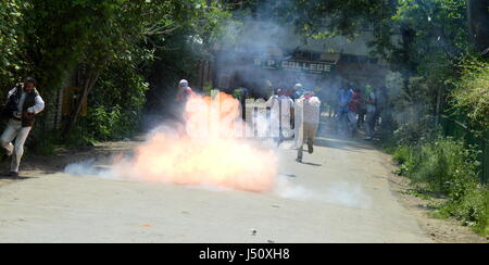 Srinagar, Kaschmir. 15. Mai 2017. Kashmiri Studenten und Videojournalist für Deckel laufen, wie eine Träne Rauch-Shell in der Nähe von ihnen bei einem Zusammenstoß mit der Polizei in Srinagar explodiert, kontrolliert indischen Kaschmir, Montag, 15. Mai 2017. Die Studenten haben mit Regierungstruppen über indische statt Kaschmir zunehmend aufeinander wurde, nachdem Truppen ein College in der südlichen Stadt Pulwama letzten Monat überfallen. Bildnachweis: Pazifische Presse/Alamy Live-Nachrichten Stockfoto