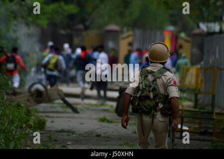 Srinagar, Kaschmir. 15. Mai 2017. Kashmiri Studenten mit Steinen werfen auf indische Polizisten wie eine Träne Rauch-Shell in der Nähe von ihnen bei einem Zusammenstoß in Srinagar explodiert, indischen Kaschmir, kontrollierten Montag, 15. Mai 2017. Die Studenten haben mit Regierungstruppen über indische statt Kaschmir zunehmend aufeinander wurde, nachdem Truppen ein College in der südlichen Stadt Pulwama letzten Monat überfallen. Bildnachweis: Pazifische Presse/Alamy Live-Nachrichten Stockfoto