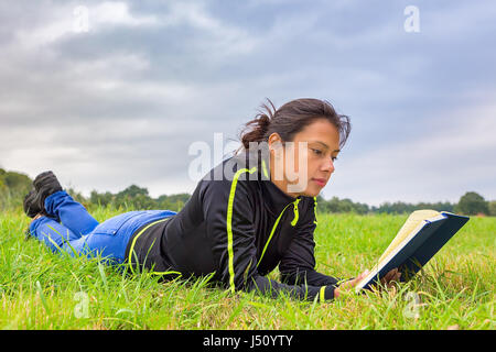 Kolumbianische Frau liegend Gras Buch Stockfoto