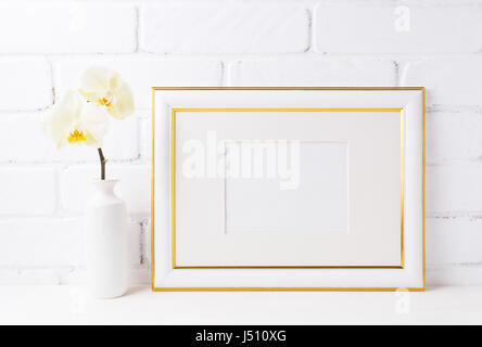 Gold geschmückten Landschaft Frame Modell mit weiche gelbe Orchidee in Vase. Leere Rahmen mock für Präsentation Kunstwerk. Template Gestaltung für moderne Kunst. Stockfoto