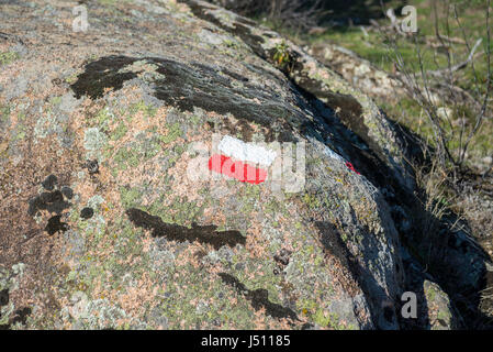 Weiße und rote Markierungen von einem Long Distance Walking Route (GR) auf einem Granit Felsen. Foto aufgenommen in La Pedriza, Guadarrama-Mountains-Nationalpark Stockfoto