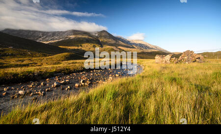 Ein felsiger Gebirgsbach fließt von den Hängen des Berges Beinn Eighe vorbei an einer verfallenen Schutzhütte Hütte in Glen Torridon in den westlichen Highlands von Schottland. Stockfoto