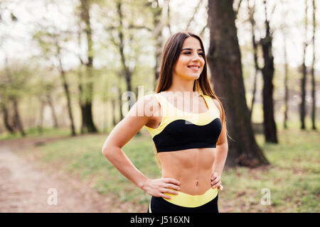 Seitenansicht des Fit junge Frau in Sportkleidung, immer bereit für Training. Gesunde Frau im Park an einem sonnigen Tag. Stockfoto