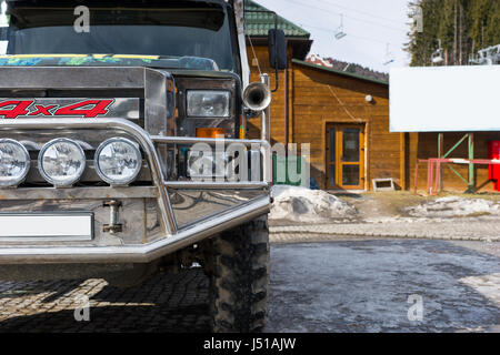 Stoßstange von einem Jeep auf dem Parkplatz neben einem Holzhaus in einem Skigebiet im Winter Stockfoto