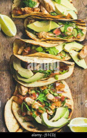 Tacos mit gegrilltem Hähnchen, Avocado, frische Salsa und Limetten über rustikalen hölzernen Hintergrund, Ansicht von oben. Gesunden low Carb und low fat Mittagessen oder Lebensmittel für com Stockfoto