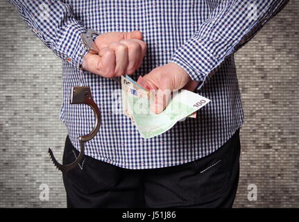 Hand mit Handschellen und Geld Stockfoto