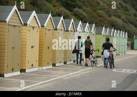 Bournemouth, UK - 11 Mai: Menschen zu Fuß durch ein Array von Strandhütten befindet sich am Strand von Bournemouth. Gesamtansicht von der Küstenstadt Bournemouth in Dorset, England. © David Mbiyu/Alamy Live-Nachrichten Stockfoto