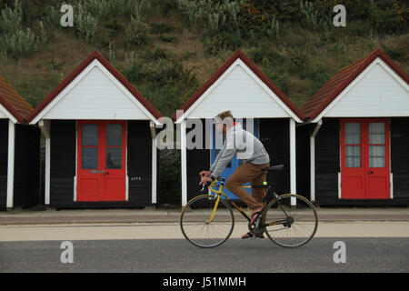 Bournemouth, UK - 11 Mai: ein Radfahrer fährt Vergangenheit eine Reihe von Strandhütten in Bournemouth Beach liegt. Gesamtansicht von der Küstenstadt Bournemouth in Dorset, England. © David Mbiyu/Alamy Live-Nachrichten Stockfoto