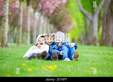 Junge Burschen auf dem Rasen im Park sitzen und Spaß haben Stockfoto