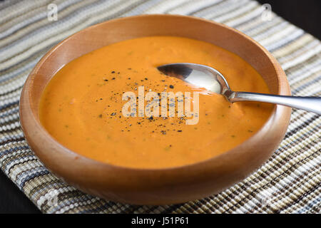 Cremige Tomatensuppe mit schwarzem Pfeffer in einer Holzschale Stockfoto