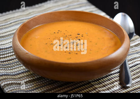 Cremige Tomatensuppe mit schwarzem Pfeffer in einer Holzschale Stockfoto