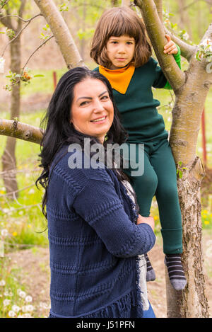 Mutter mit ihrem Sohn Klettern im Baum Spaß im Garten Stockfoto