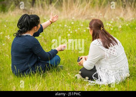 Zwei Frauen, die Unterhaltung in der Natur und die Brünette Frau, die etwas zu Hügeln Stockfoto