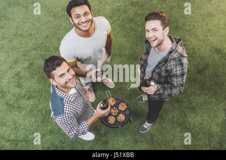 Draufsicht der glückliche junge Freunde, trinken Bier und Grill zu machen Stockfoto