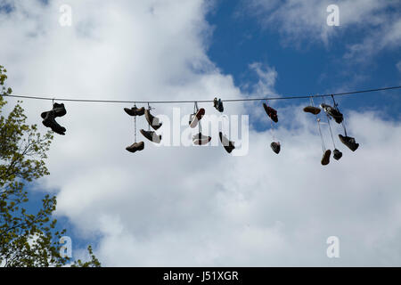 Schuhe und Stiefel, die über eine Straße auf einem elektrischen Draht hängen. Stockfoto