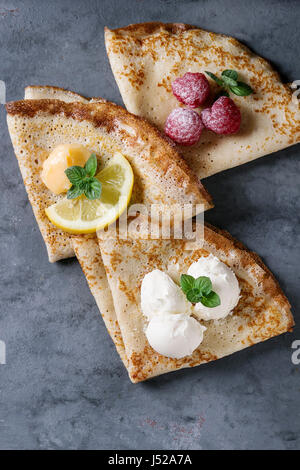 Süße Crêpes Pfannkuchen mit verschiedenen Füllungen frische Himbeeren, Zitroneklumpen, Mascarpone Käse, Minze, Puderzucker über grau blau Metall Textur backgr Stockfoto