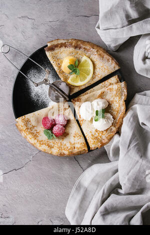 Süße Crêpes Pfannkuchen mit verschiedenen Füllungen frische Himbeeren, Zitroneklumpen, Mascarpone Käse, Minze, Puderzucker mit Vintage Sieb, Textile Leinen o Stockfoto