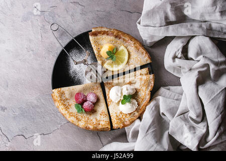 Süße Crêpes Pfannkuchen mit verschiedenen Füllungen frische Himbeeren, Zitroneklumpen, Mascarpone Käse, Minze, Puderzucker mit Vintage Sieb, Textile Leinen o Stockfoto