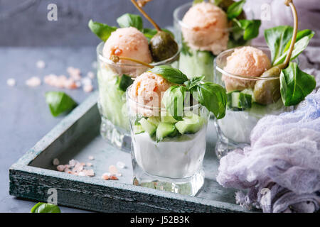 Verrines Vorspeise mit Lachspastete, roter Kaviar, Gurke, Frischkäse, Kräuter, Kapern in Gläsern serviert auf Holztablett mit rosa Salz und Basilikum über Stockfoto