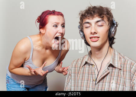 Frau schreit ihr Ehemann. Mann mit Kopfhörern Musik hören Stockfoto