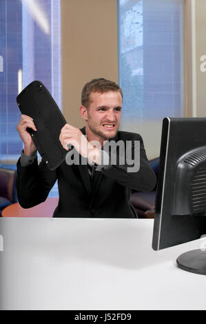 Verärgerter Mann mit einem Desktop-Computer für Unternehmen Stockfoto