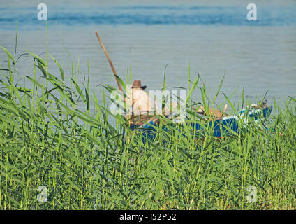 Traditionellen ägyptischen Beduinen Angler im Ruderboot am Fluss Nil Fischen vom Ufer Schilfgras Stockfoto